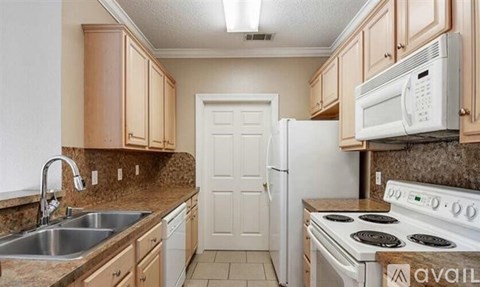 A kitchen with a white stove, sink, and cabinets.