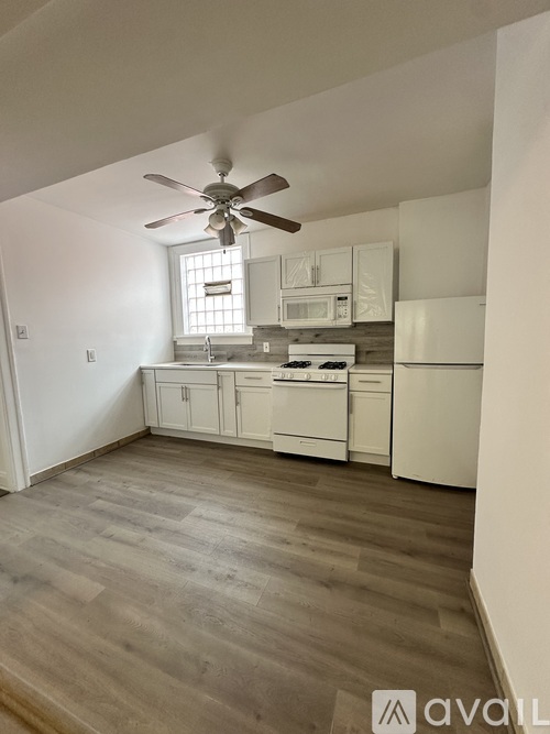 A kitchen with white cabinets and a fan on the ceiling.