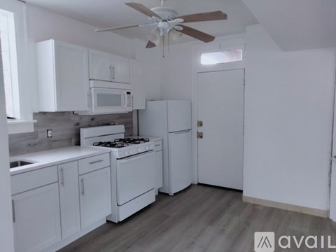 A kitchen with white cabinets and a fan on the ceiling.