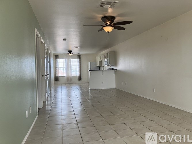 A spacious room with a ceiling fan and tiled flooring.