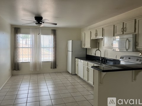 A kitchen with white cabinets and a black countertop.