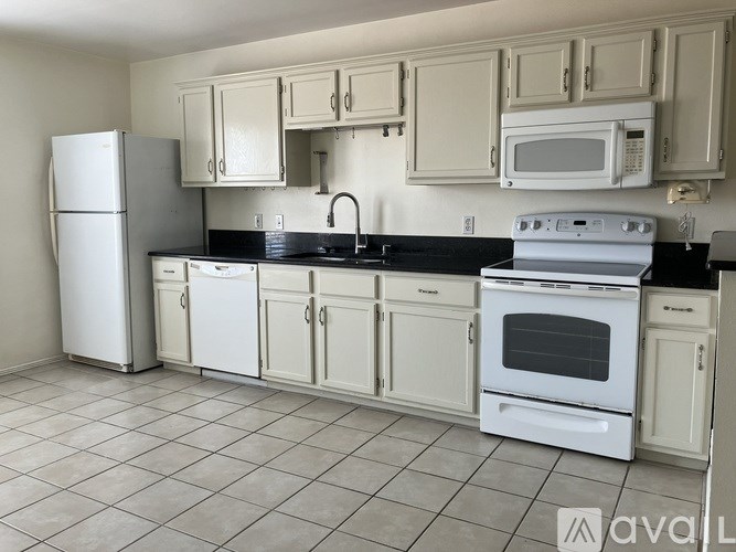 A kitchen with white appliances and cabinets.