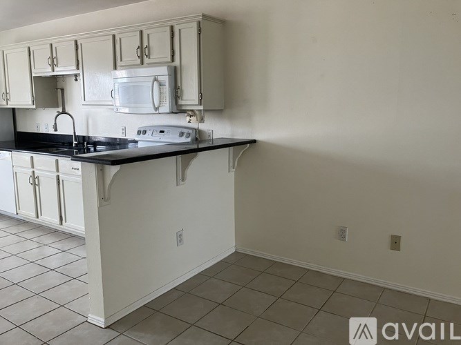 A kitchen with white cabinets and a black countertop.