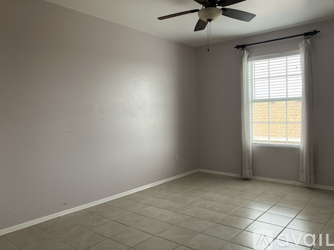 A room with a ceiling fan and a window with curtains.