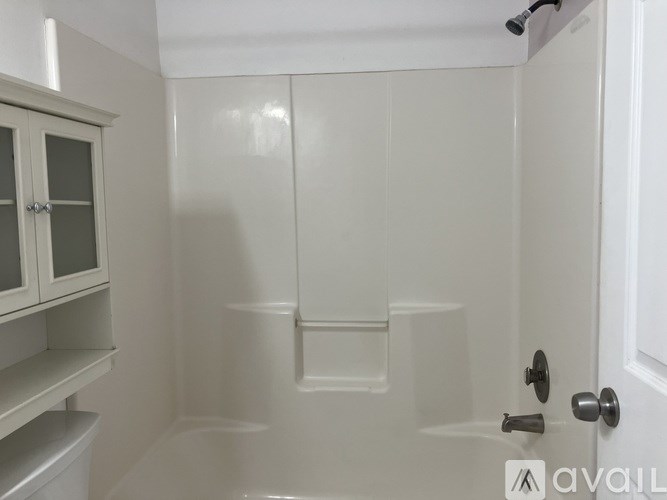 A white bathroom with a glass shower door and a toilet.