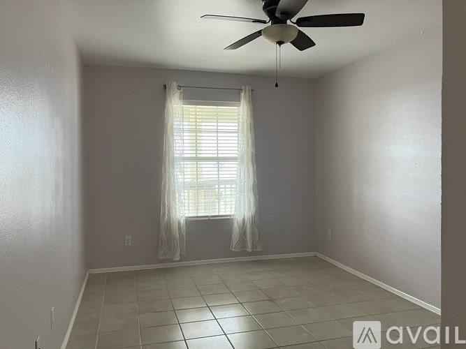 A room with a ceiling fan and a window with curtains.