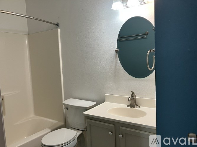A bathroom with a toilet, sink, and mirror.