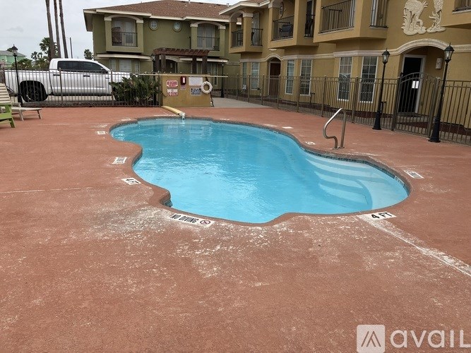 A pool with a red bottom and a blue top is surrounded by a black fence.
