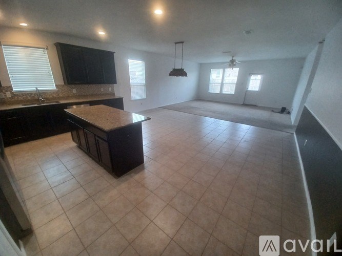 A large, empty room with a kitchen area and a bar area.