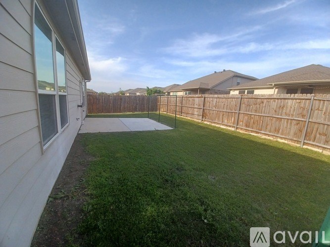 A backyard with a wooden fence and a green lawn.