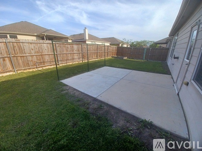 A backyard with a wooden fence and a concrete patio.