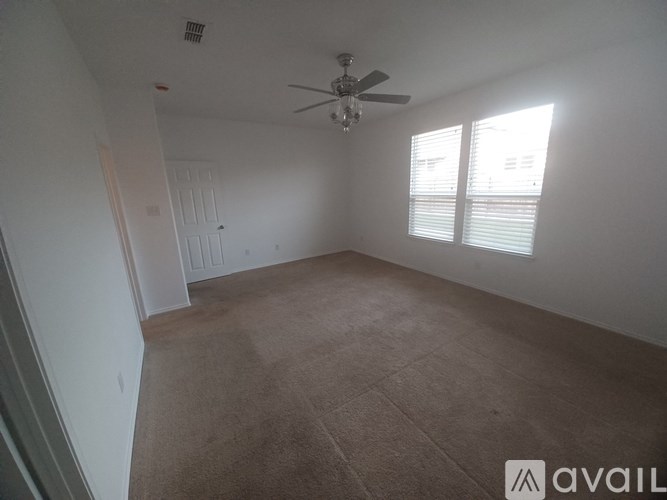A room with a ceiling fan and carpeted floor.