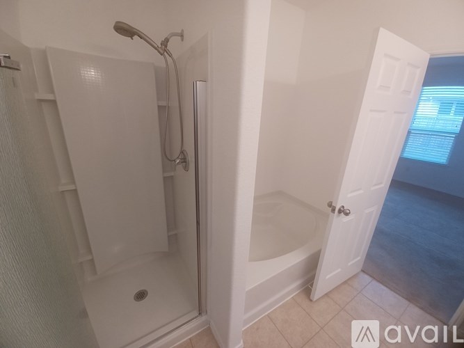 A bathroom with a walk-in shower and a doorway leading to another room.
