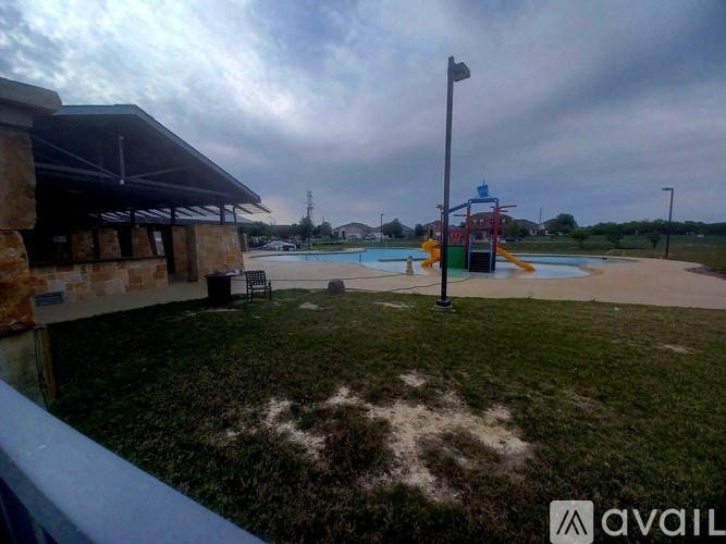 A playground with a slide and a building in the background.