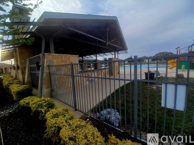 A patio area with a black metal fence and a grey roof.