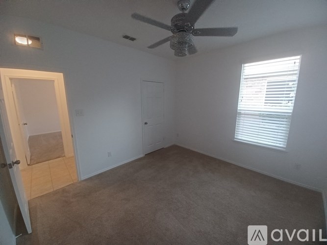 A room with a ceiling fan and a window with blinds.