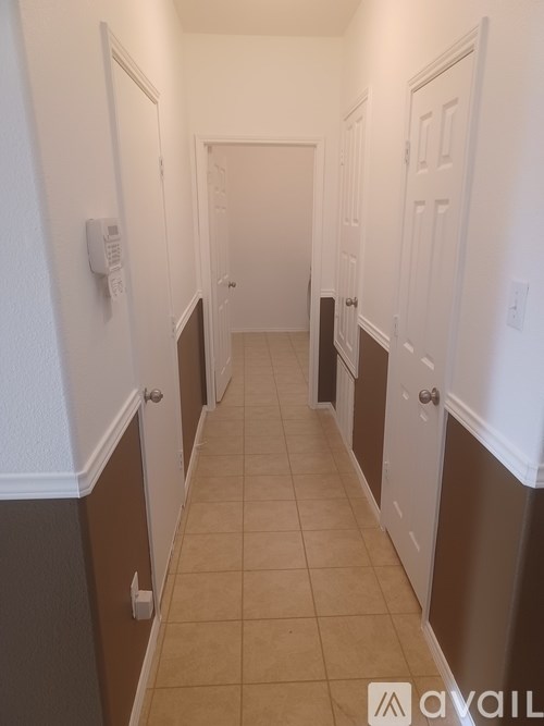 A hallway with white walls and brown trim.