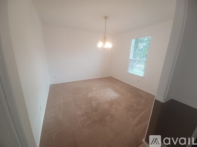 A room with a brown floor and a window with blinds.