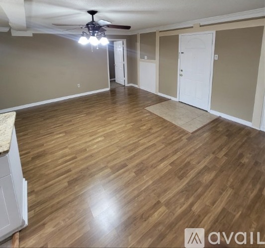 A spacious room with wooden flooring and a ceiling fan.