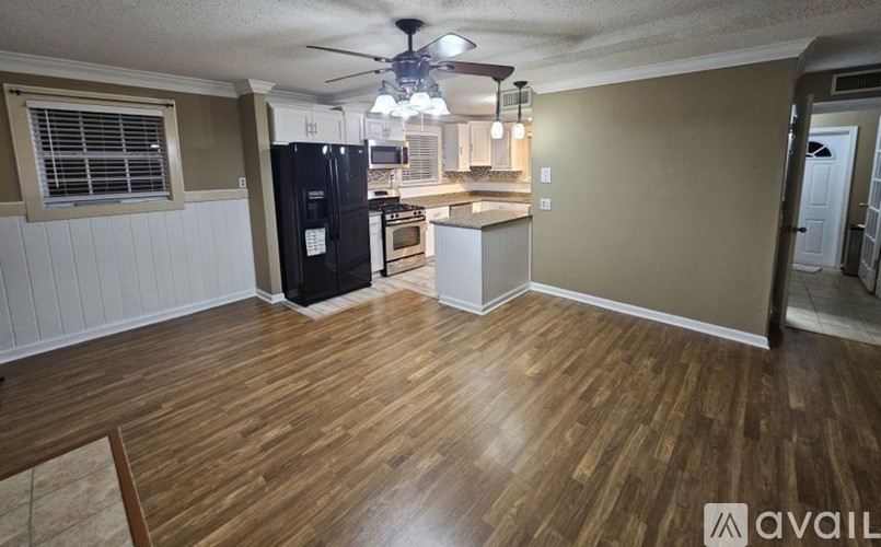 A kitchen with a black fridge and wooden floors.