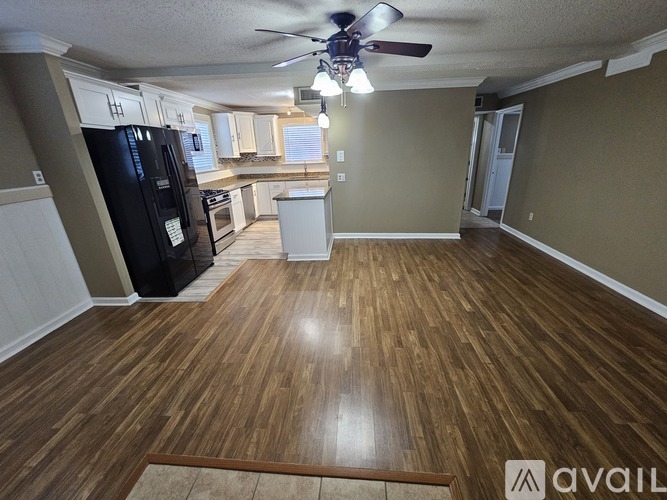 A kitchen with a black fridge and wooden floors.