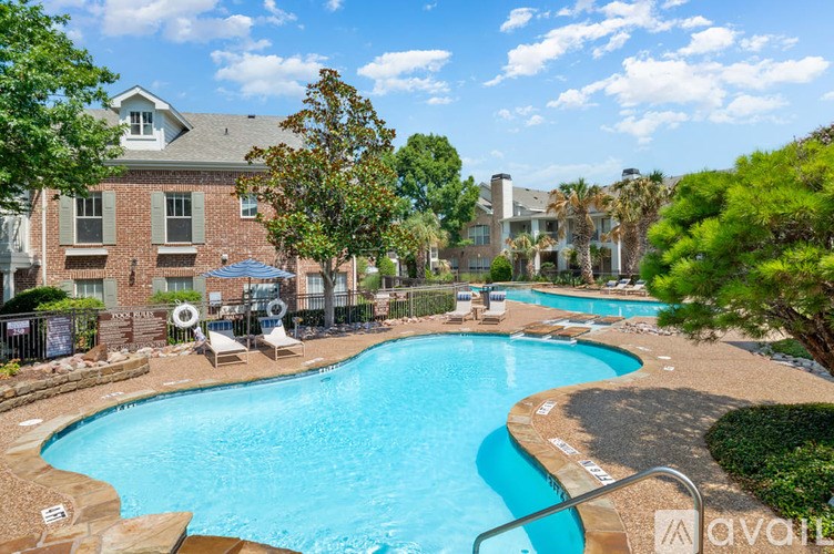 A swimming pool surrounded by trees and chairs with a building in the background.