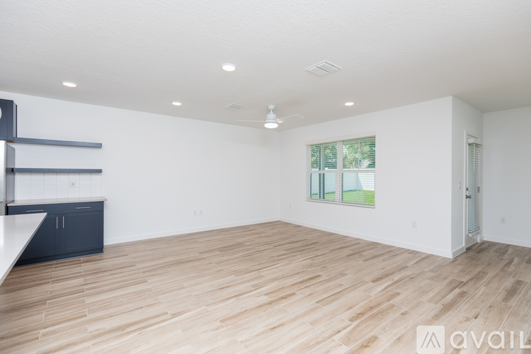 A spacious room with wooden flooring and white walls.