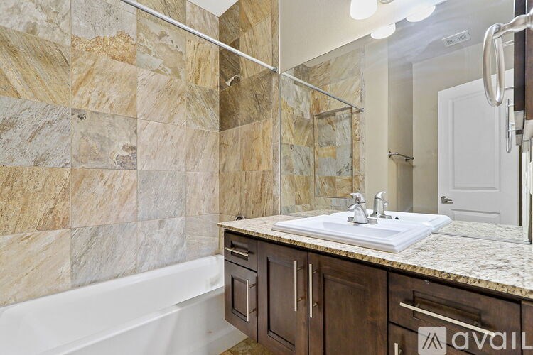 A bathroom with a marble tile wall and a white sink.