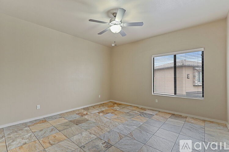 A room with a ceiling fan and a window with blinds.