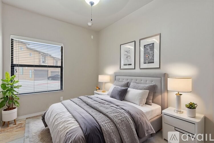A bedroom with a large bed, two nightstands, and a window with blinds.