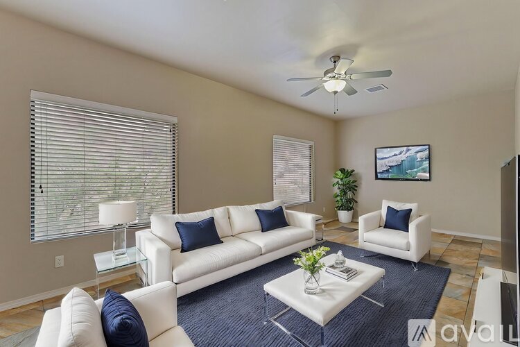 A living room with white furniture and a ceiling fan.