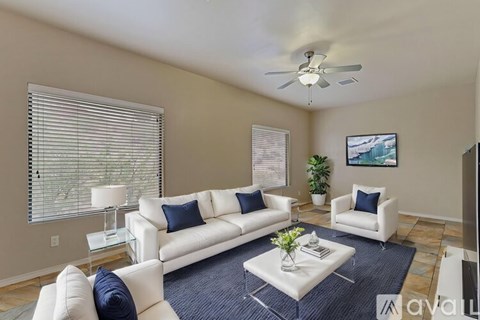 A living room with white furniture and a ceiling fan.