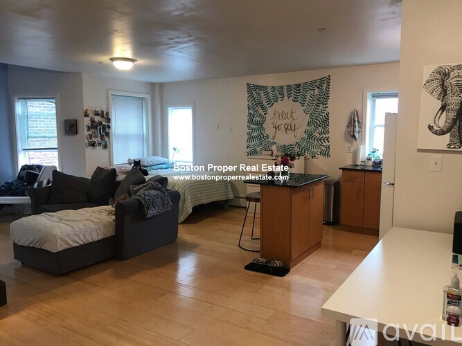 A living room with a couch, a bed, and a kitchen area.