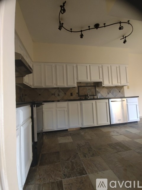 A kitchen with white cabinets and a tiled floor.