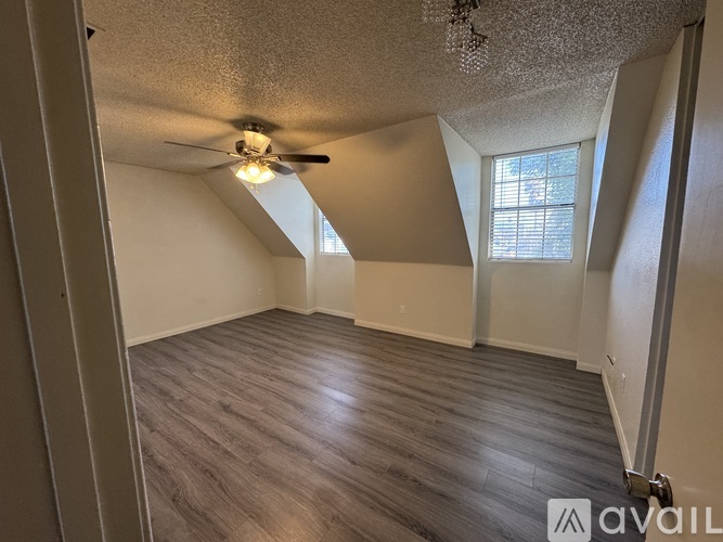 A room with a ceiling fan and wooden flooring.
