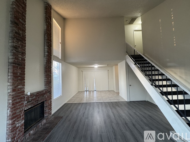 A spacious living room with a fireplace and a staircase.