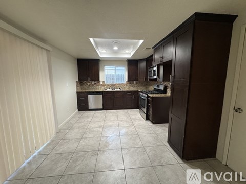 A kitchen with brown cabinets and a tiled floor.