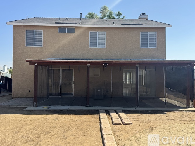 A house with a brown stucco exterior and a covered patio area.