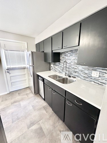 A kitchen with black cabinets and a stone backsplash.