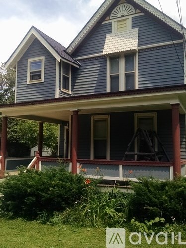 A blue house with a porch and a sign in front of it.