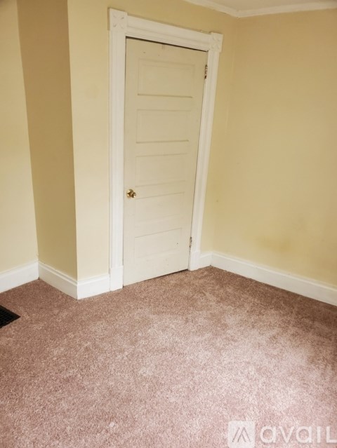 A room with a white door and carpeted floor.