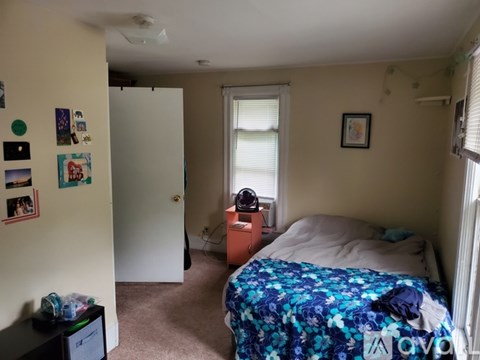 A bedroom with a bed, dresser, and a window with blinds.