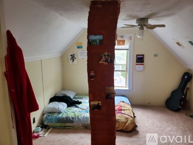 A room with a bed, a ceiling fan, and a guitar.