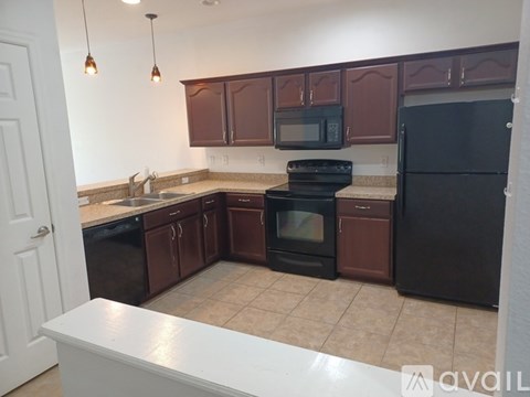A kitchen with brown cabinets and black appliances.