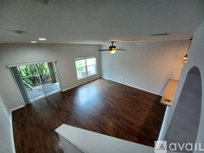 A room with a ceiling fan and sliding glass doors.