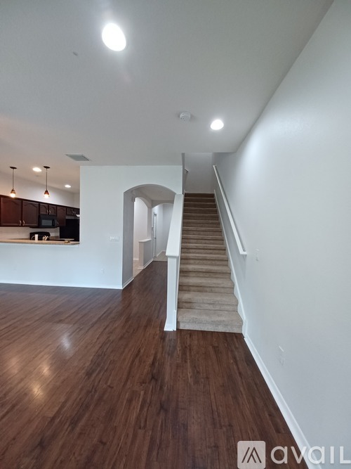 A staircase with a beige carpeted runner leads up to a landing with a white wall and a window.