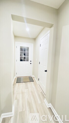 A hallway with a white door and a wooden floor.