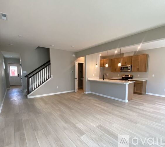 A spacious open floor plan with a kitchen area and a staircase.