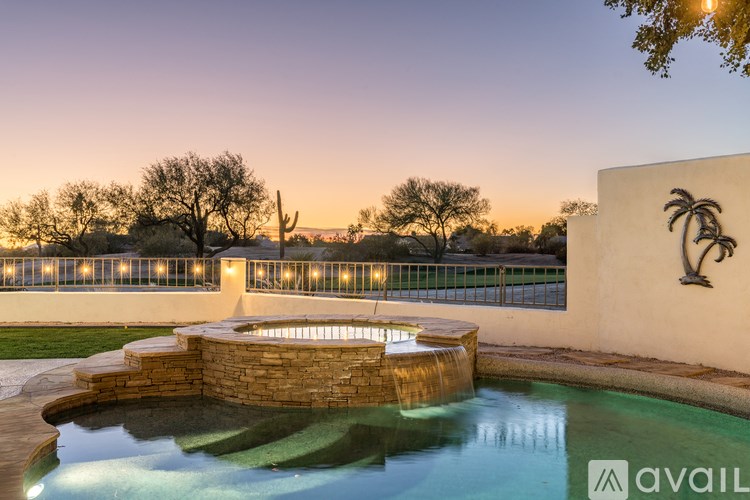 A pool with a waterfall and lights on the wall.