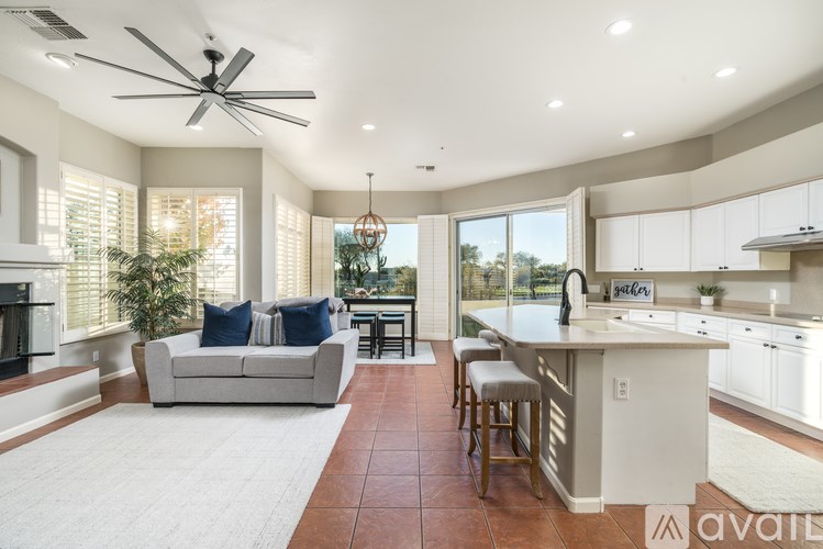 A spacious living room with a fireplace and a kitchen area in the background.